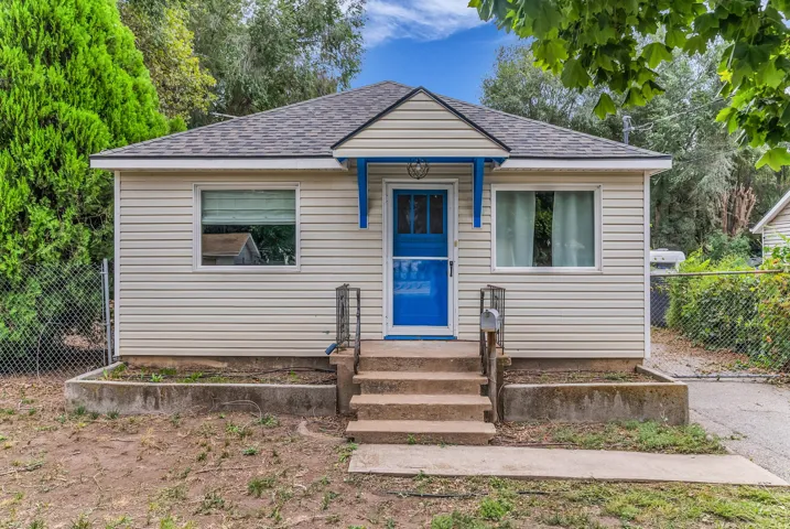Gable roofline with asphalt shingles, horizontal vinyl siding, a vibrant blue entry door, and a covered porch entry