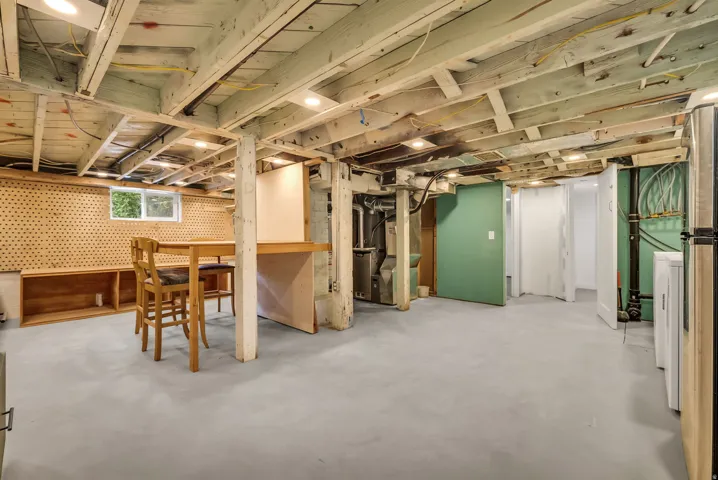 Expansive basement area with exposed ceiling beams and recessed lighting
