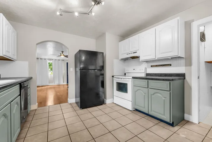 Kitchen featuring tile flooring, white upper cabinetry, complementary lower cabinetry, and dark countertops