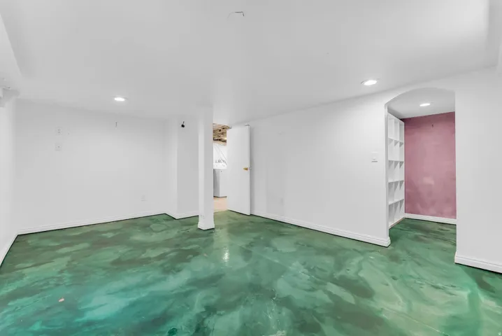 Recessed lighting, painted concrete flooring, arched doorway, and built-in shelving