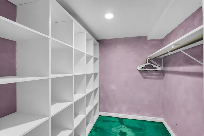 Built-in shelving, integrated hanging rod, recessed lighting, and green flooring