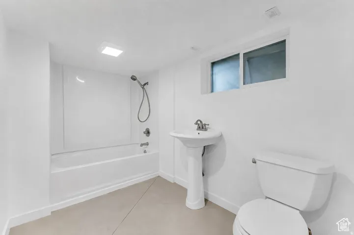 Full bath featuring a tub/shower combination, pedestal sink, toilet, and a window