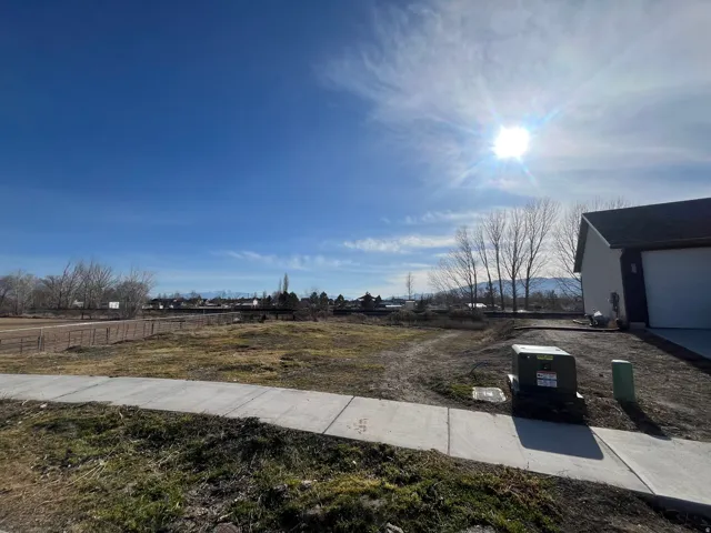 Expansive lot featuring a concrete sidewalk and partial residential structure