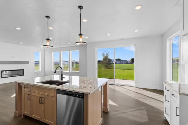 Kitchen island with stone countertop, undermount sink, and stainless steel dishwasher