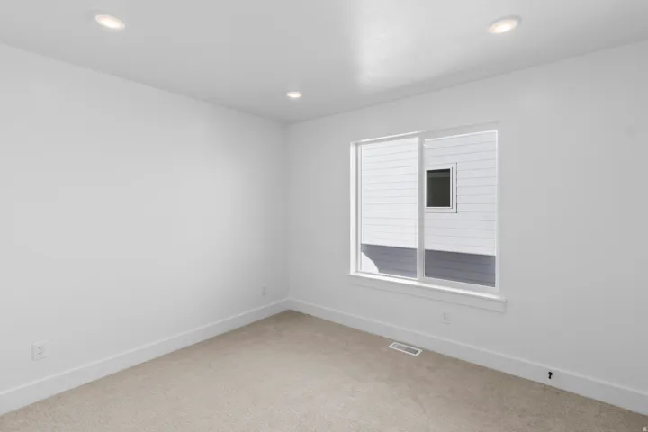 Recessed ceiling lighting, neutral carpet flooring, a large window with white trim, and white painted walls