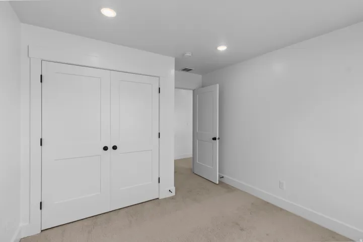 Plush carpeted flooring, recessed ceiling lighting, flat-panel interior doors with matte black hardware, and crisp white trim