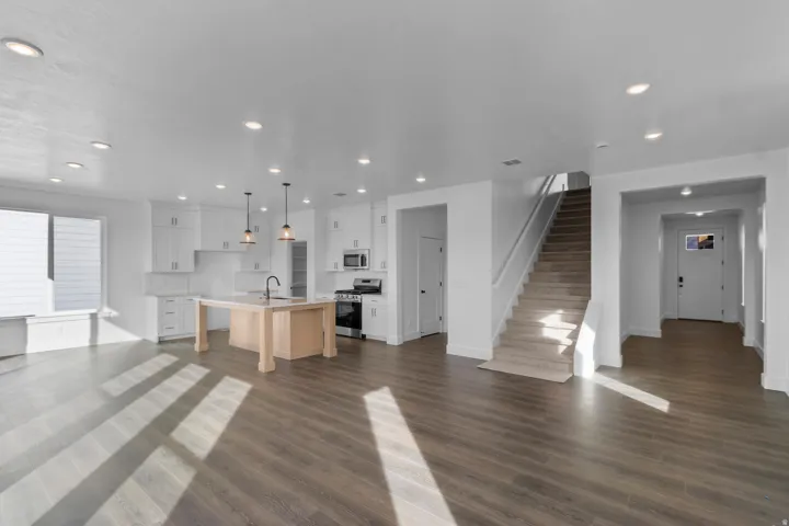 Open-concept living area featuring wood-finish flooring, recessed lighting, and white cabinetry