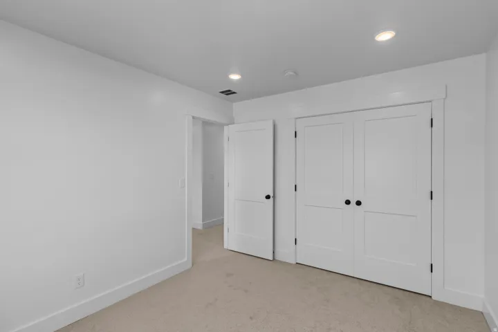 Recessed ceiling lighting, paneled interior doors with matte black hardware, and neutral carpeting