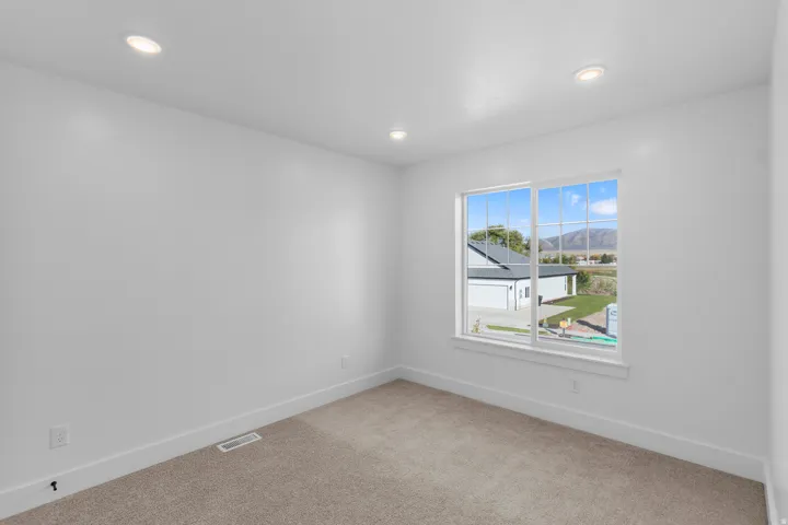 Recessed ceiling lighting, neutral carpet flooring, and a large window with white trim