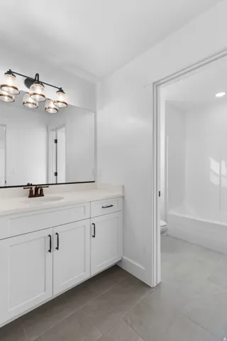 White shaker cabinetry with dark hardware, a single basin sink, and a light-toned countertop