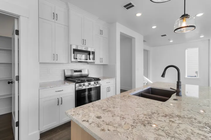Kitchen featuring light-toned cabinetry, stainless steel appliances, a subway tile backsplash, a large island with a dual-basin sink, and recessed lighting