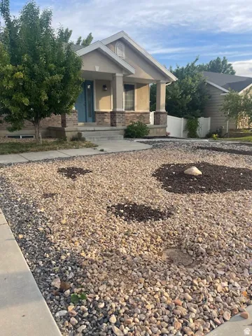 Stucco exterior with brick accent, front porch, concrete walkway, and rock landscaping