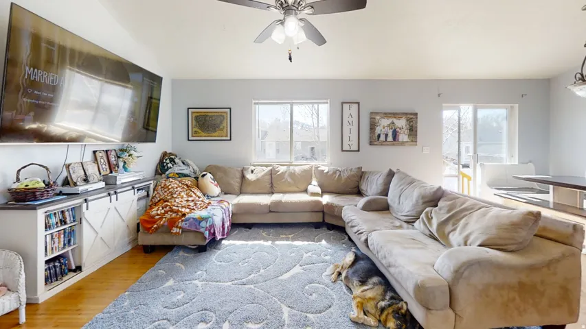 Vaulted ceiling, ceiling fan, wood-finish flooring, built-in media console with barn-door style fronts, sliding glass door