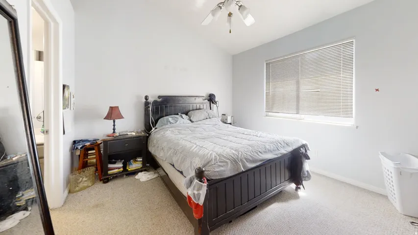 Neutral wall color, window with horizontal blinds, overhead ceiling fan, carpeted flooring, and a permanent door frame