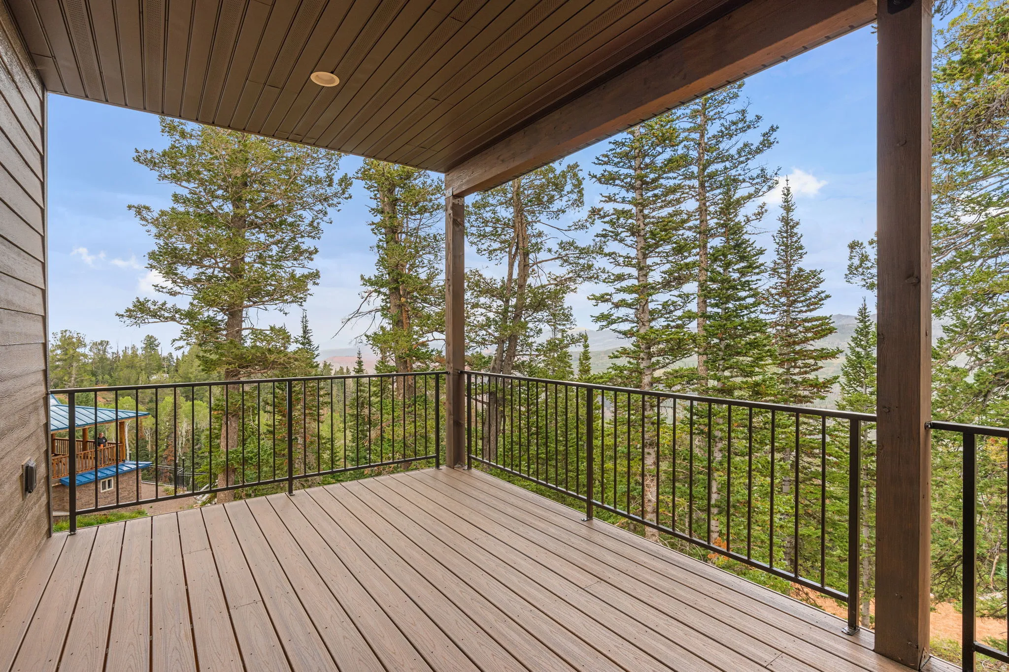 Covered outdoor deck with composite decking, recessed lighting, wood-paneled ceiling, and metal railings