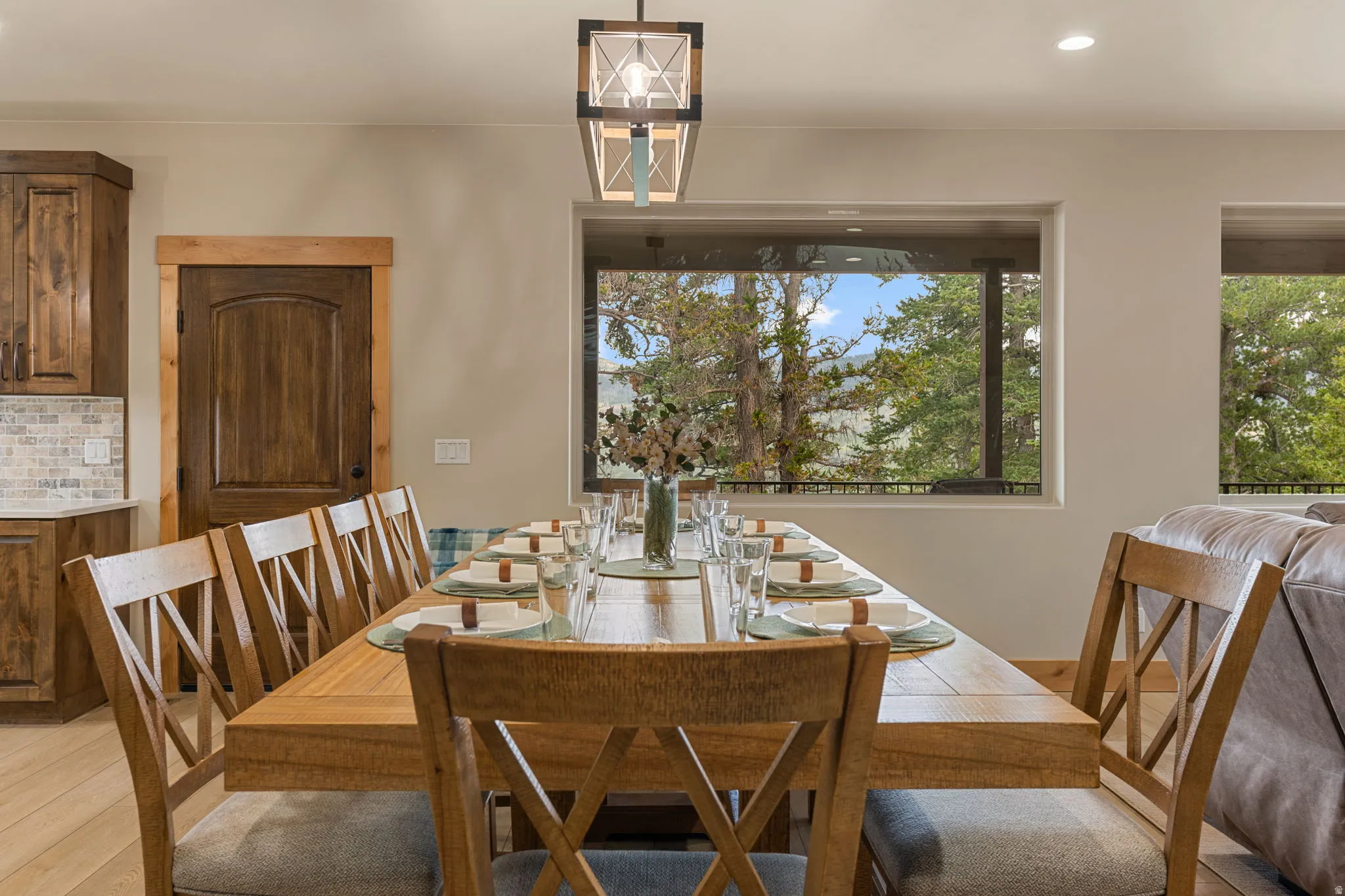 Recessed lighting, wood-finish flooring, wood-paneled interior door with trim, kitchen cabinetry with subway tile backsplash, and transom windows
