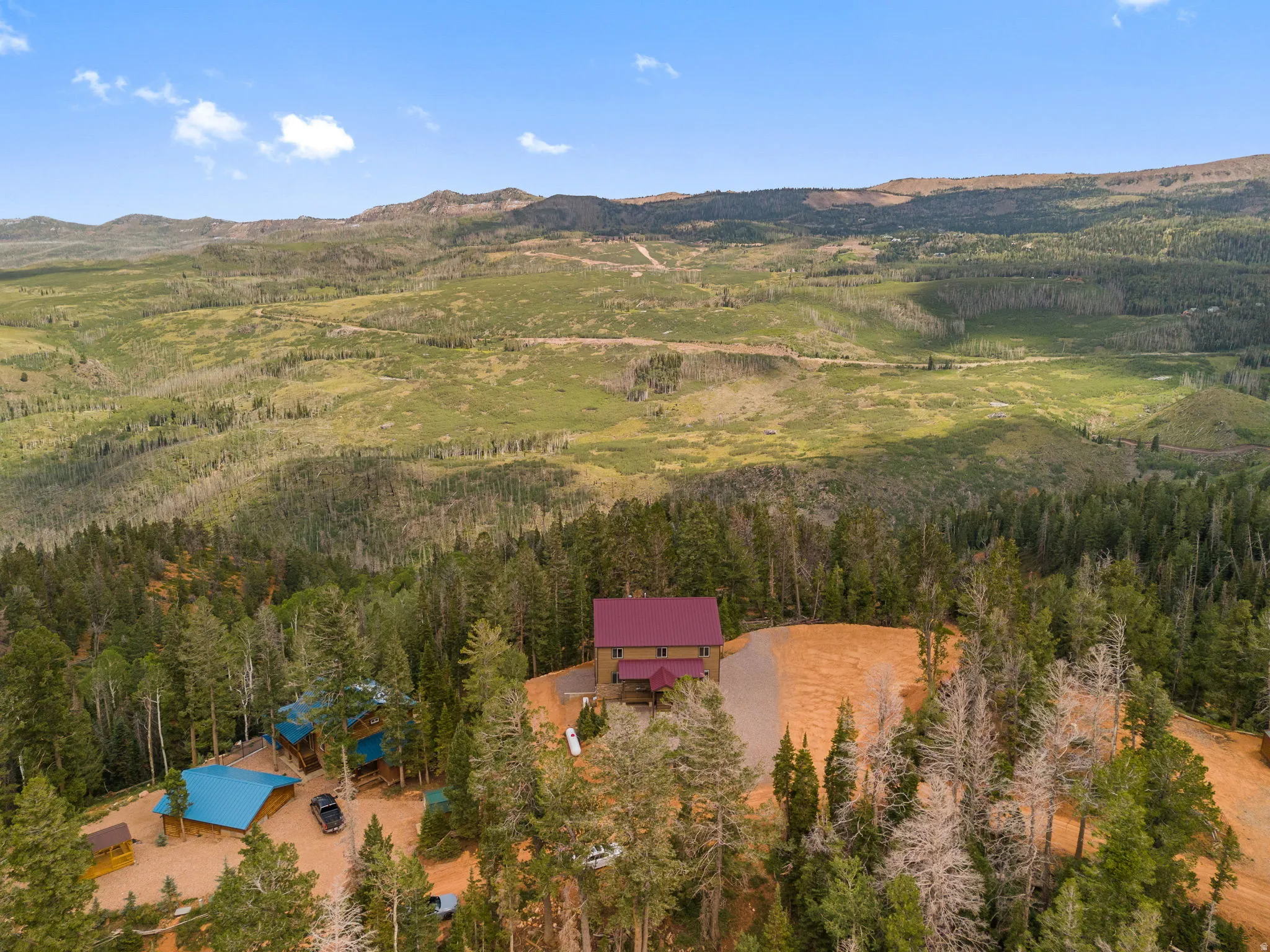 Expansive mountain landscape with a residence featuring a red roof