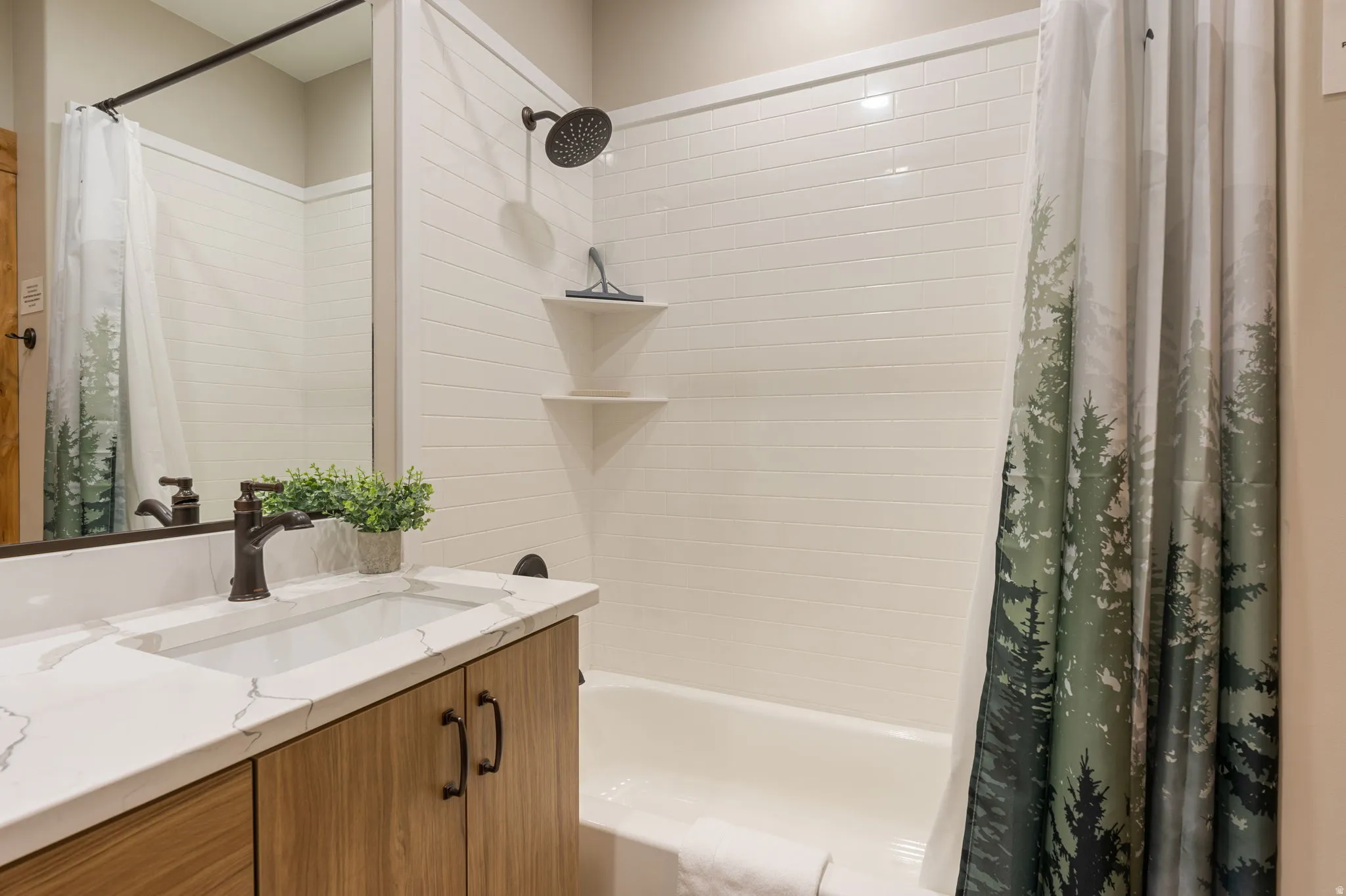 White subway tile shower surround with integrated shelving and a dark bronze shower head