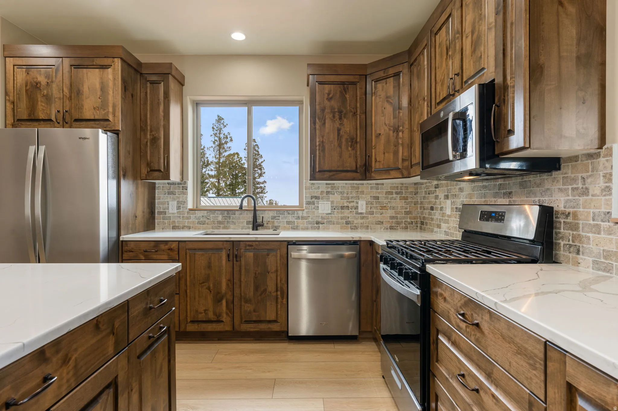Kitchen featuring full-height wood cabinetry, stainless steel appliances, white countertops, and a tiled backsplash