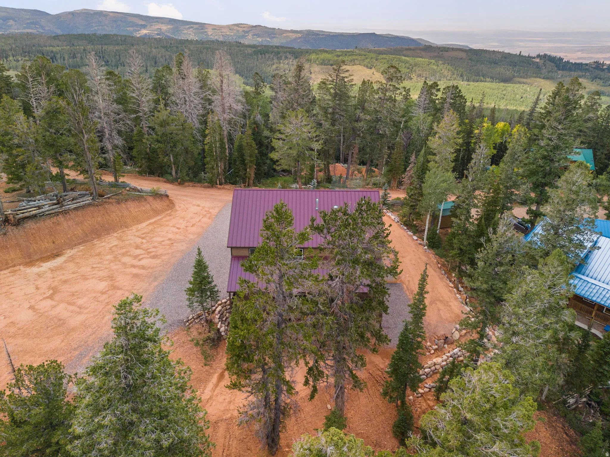 Mountain property with a vibrant purple metal roof and mature evergreen trees