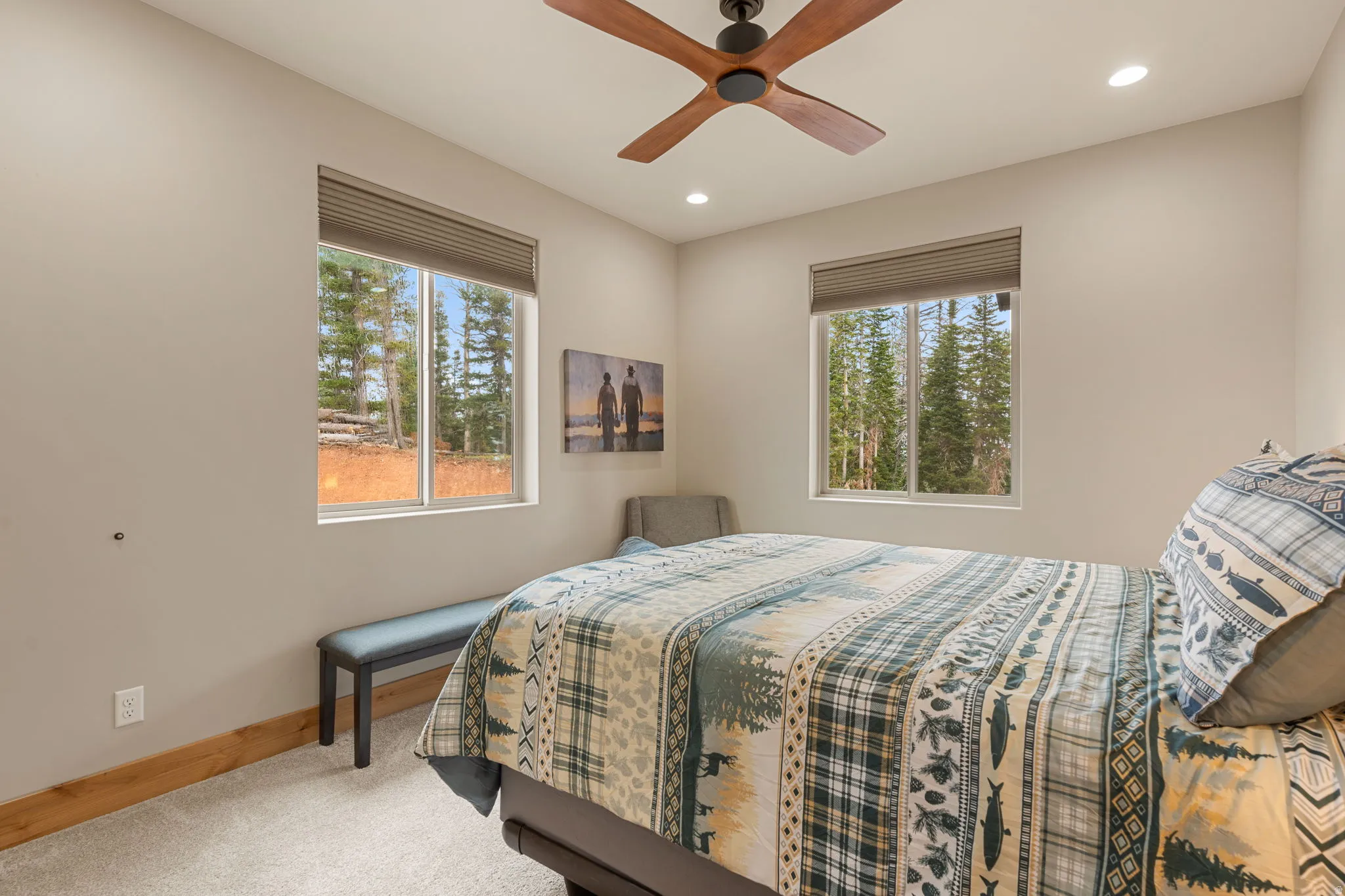 Recessed lighting, wood-finish ceiling fan, two windows with forest scenery, and natural wood trim