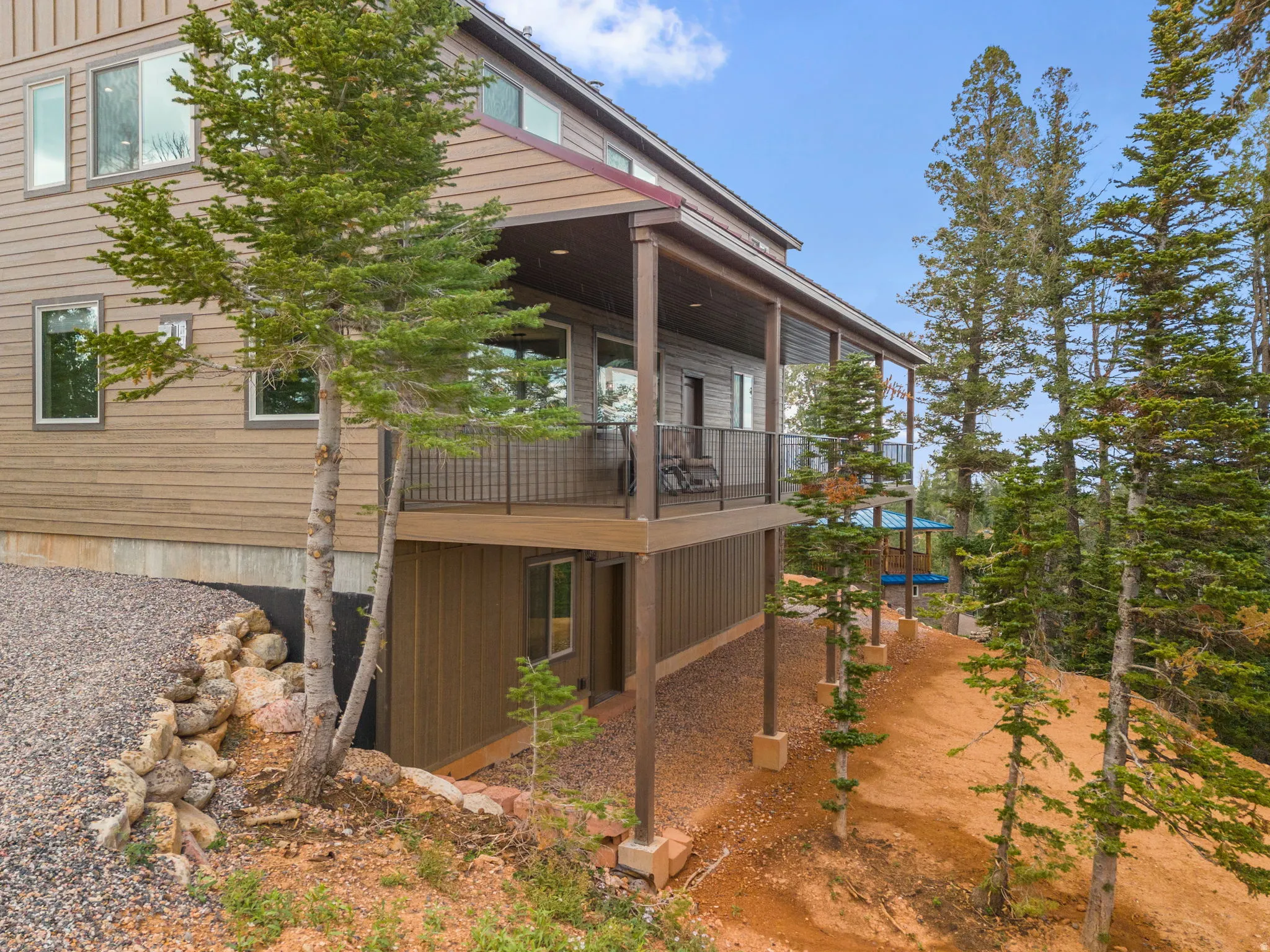 Multi-level exterior with horizontal siding, covered deck with black railing, and a ground-level entrance