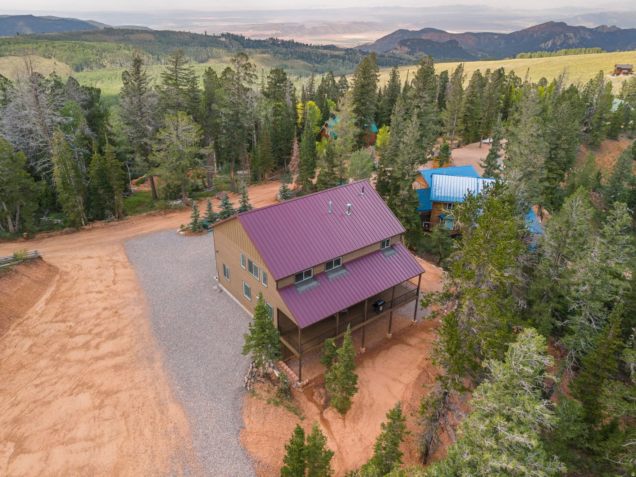 Two-story property with a red metal roof, a covered porch, and a gravel driveway