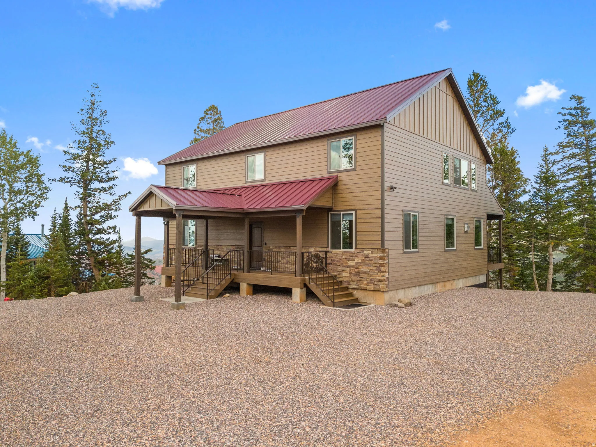 Two-story residence featuring a red metal roof and neutral-toned siding