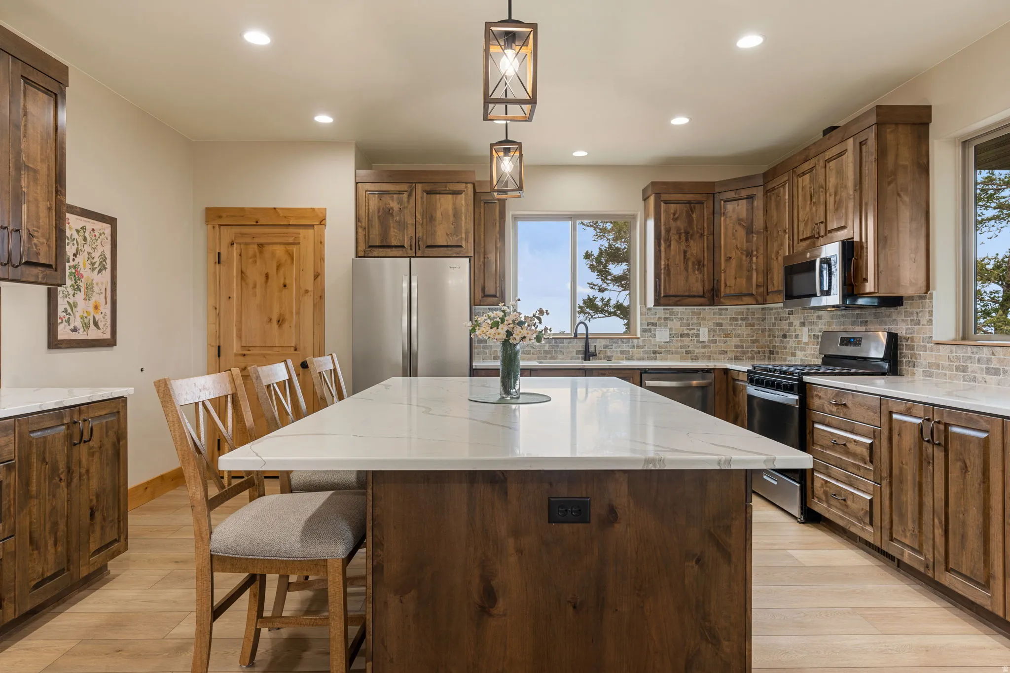 Kitchen featuring wood cabinetry, stainless steel appliances, a large island with a light-toned countertop, and recessed lighting