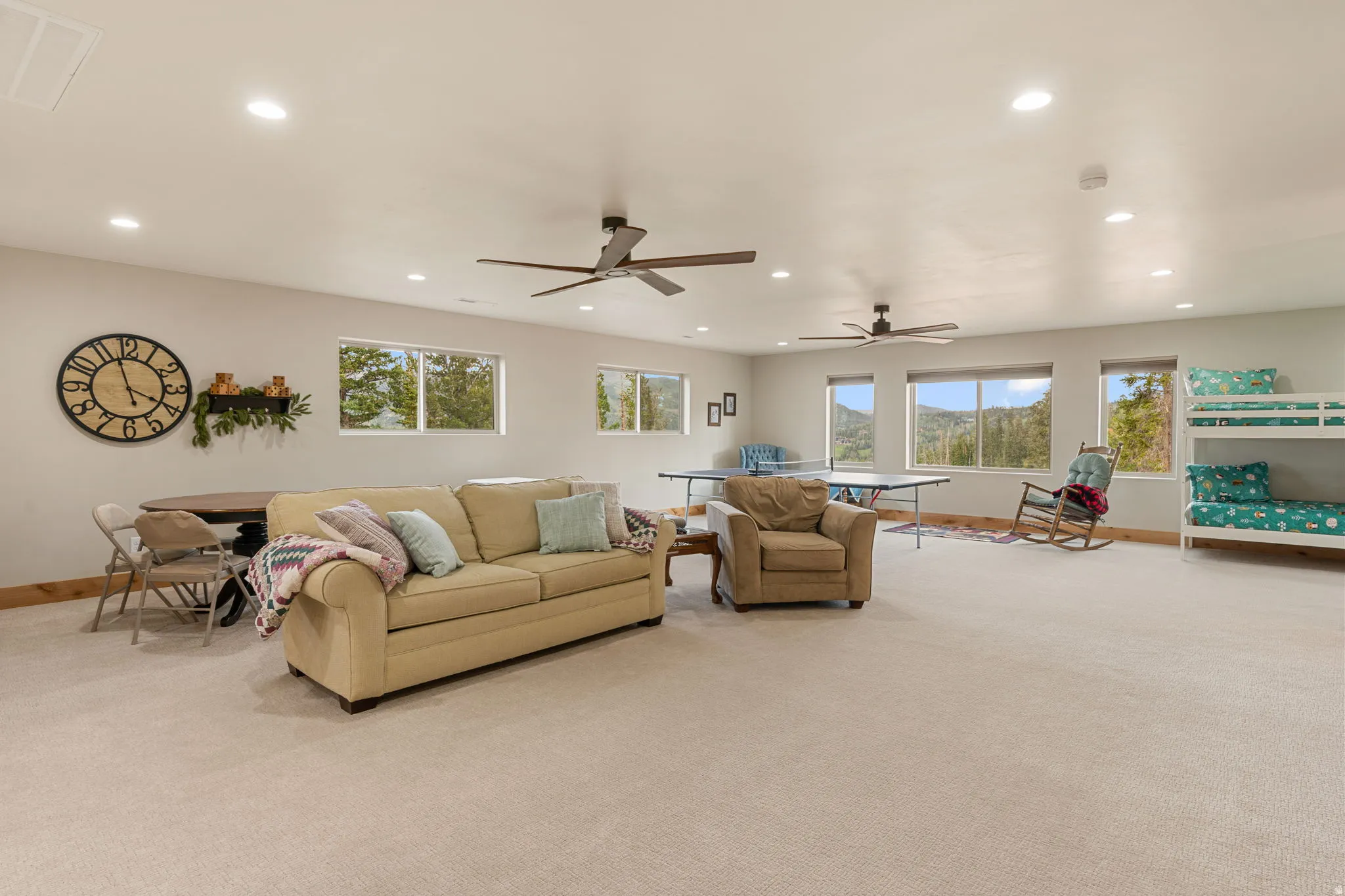Expansive open-plan room with recessed lighting, multiple windows, and two ceiling fans