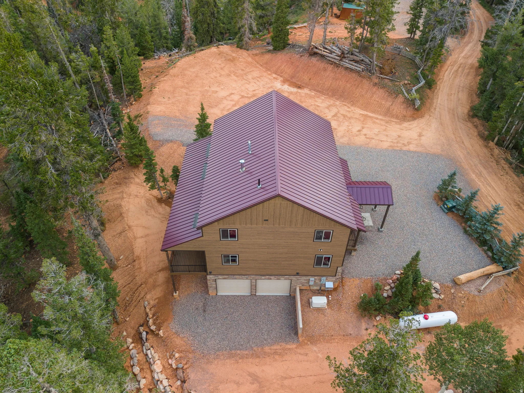 Multi-level residence featuring a dark red metal roof and light brown siding