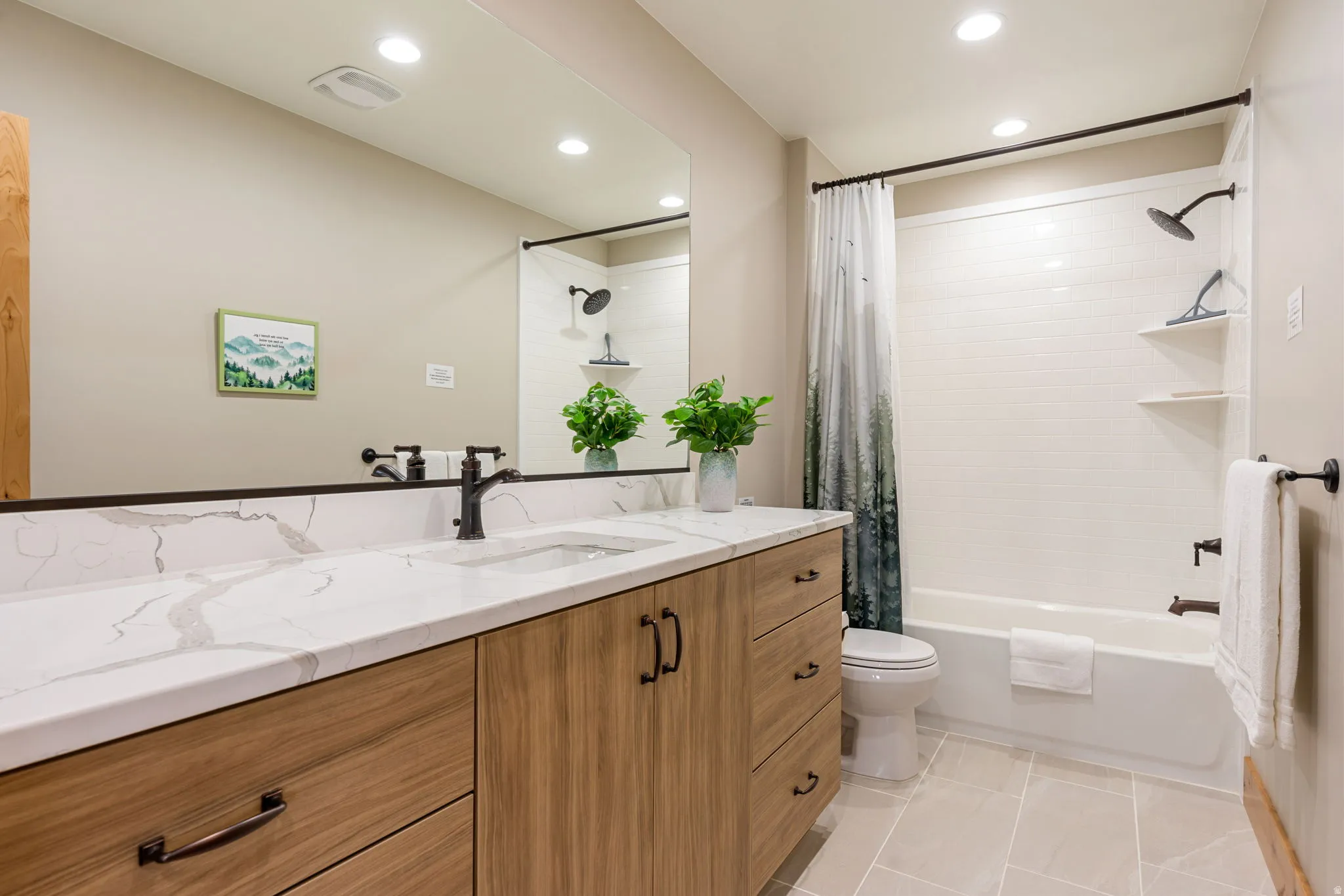 Double vanity with a white countertop, wood-finish cabinetry with dark hardware, and a large mirror