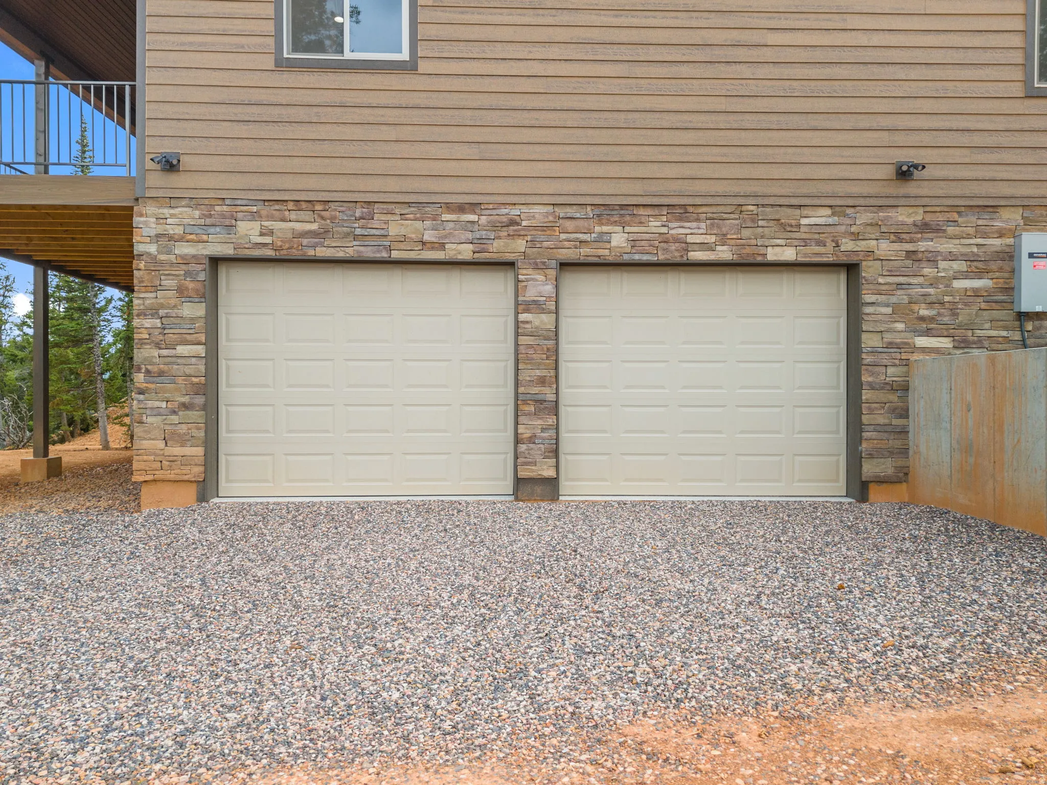 Two panel garage doors with stacked stone facade and horizontal siding