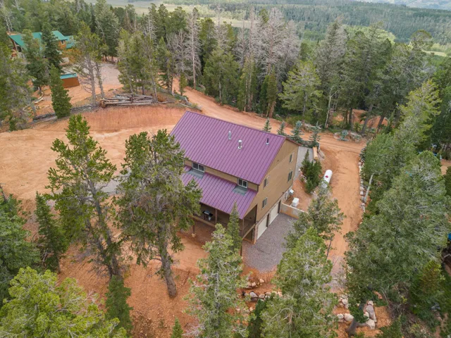 Two-story residence with a purple metal roof, tan siding, and a gravel driveway