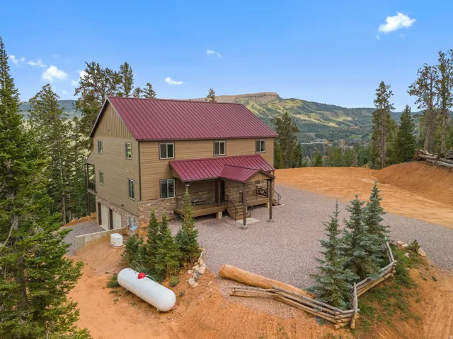 Mountain-style residence featuring a red metal roof, stone veneer accents, and wood siding