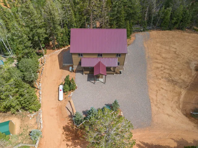 Two-story property with a red metal roof, surrounded by mature trees