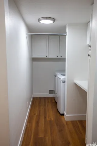 Laundry area featuring white cabinetry, a built-in hanging rod, wood-finish flooring, and a white built-in countertop
