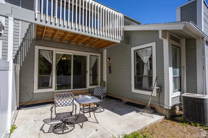 Concrete patio with a privacy fence, accompanied by multiple windows and a sliding glass door