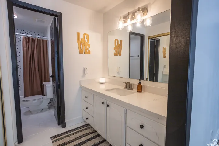 White vanity with multiple drawers and cabinet storage, single basin sink, and a large wall-mounted mirror