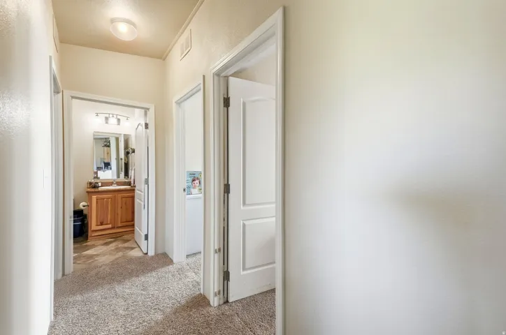 Recessed lighting fixture, light-toned wall paint, carpeted flooring, wood-finish vanity with countertop, wall-mounted light fixture
