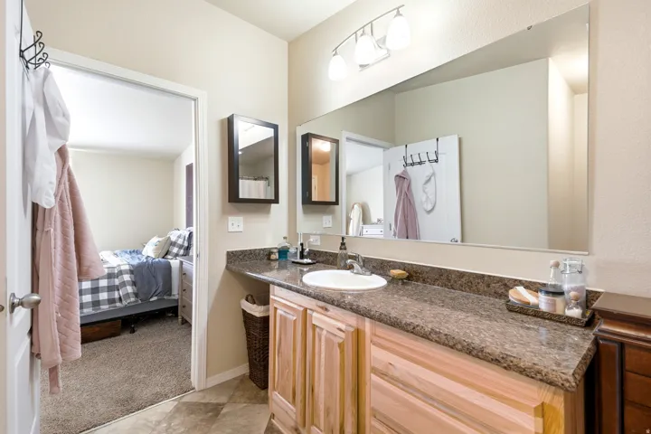 Bathroom vanity with light wood cabinetry, a built-in sink, and a speckled countertop
