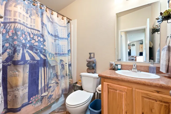 Bathroom featuring a single vanity with a laminate countertop, an integrated sink, and wood-finish cabinetry
