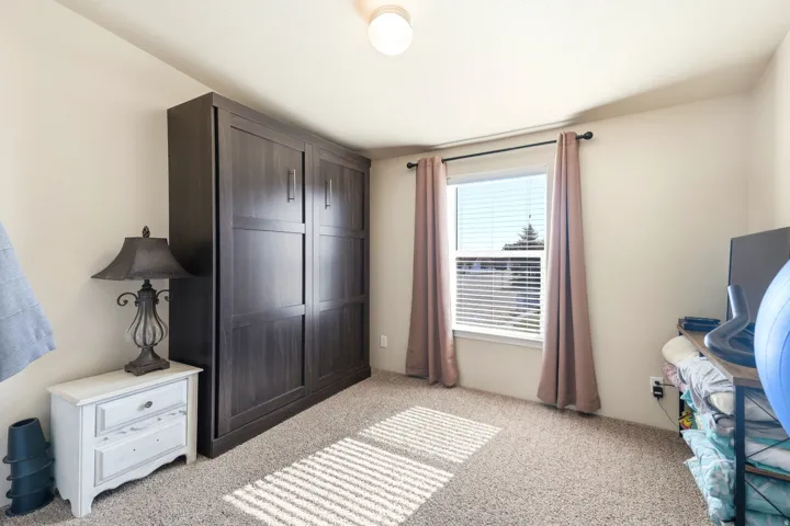 Built-in dark wood-finish cabinetry, carpeted flooring, and a window with blinds