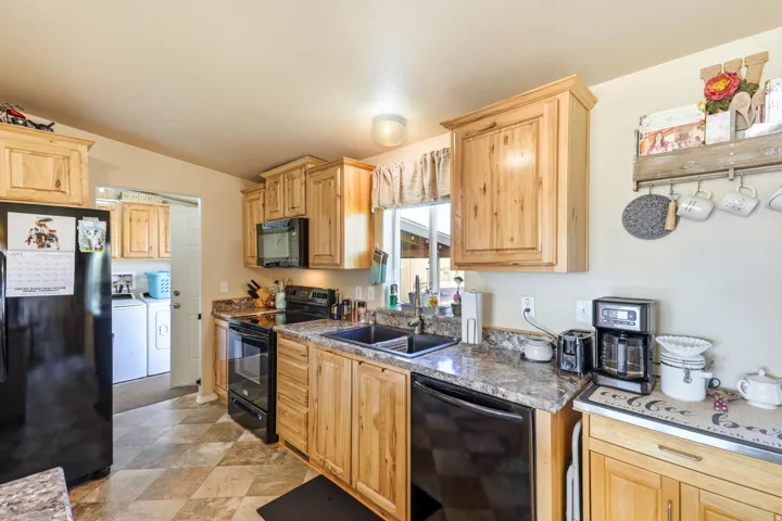 Spacious kitchen featuring wood cabinetry, granite countertops, and black stainless steel appliances including a dual-oven range and refrigerator