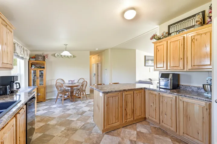 Kitchen featuring wood cabinetry, stone-finish countertops, a built-in sink, and checkerboard floor tiling