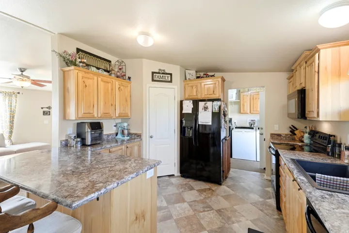 Kitchen featuring wood cabinetry, stone-look countertops, a built-in microwave, and tile-look flooring