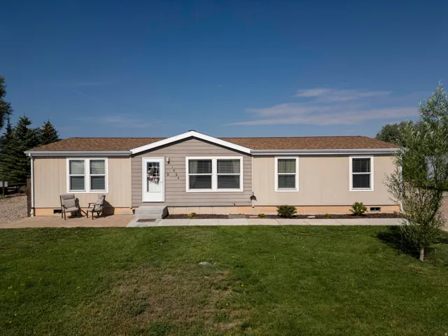 Charming manufactured home featuring a gabled roofline with contrasting trim, horizontal siding exterior, and multiple double-hung windows providing natural light