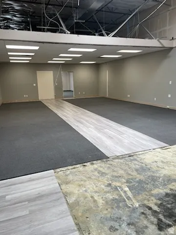 Open-concept space with recessed lighting, exposed ceiling framework, light gray wall paint, and a combination of carpet and wood-finish flooring