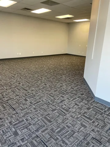 Expansive open-concept space featuring patterned carpeting, neutral wall tones, and recessed ceiling lighting