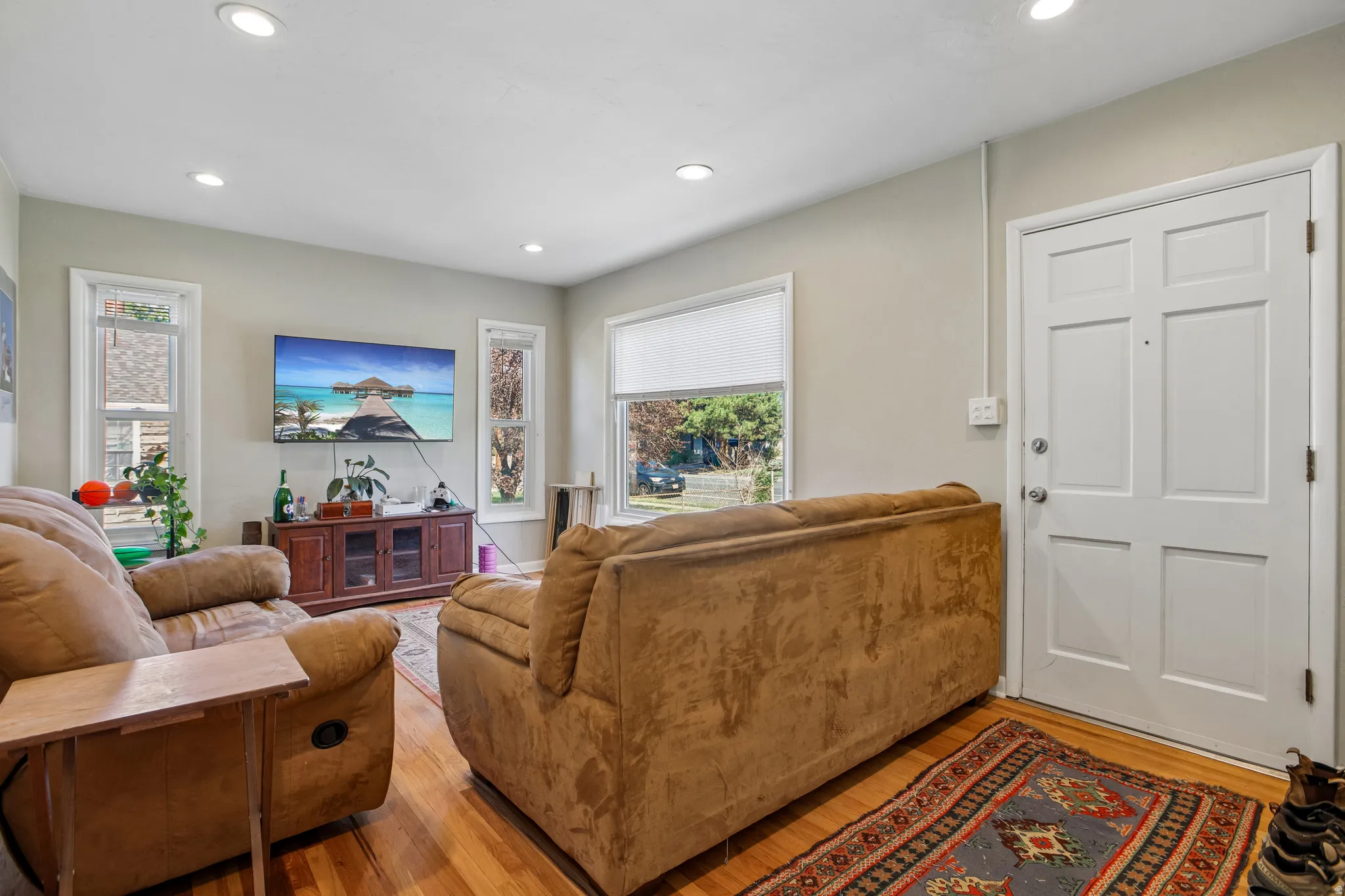 Hardwood flooring, recessed lighting, multiple windows, and a paneled entry door